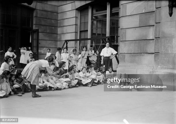 Teacher watches over a bowling game of ten pins for a class of young girls, United States, ca.1920s.