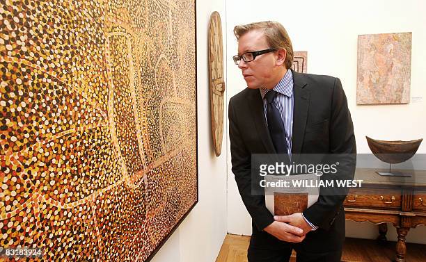 Sotheby's head of Aboriginal Art, Tim Klingender, inspects a painting by famous Aboriginal artist Emily Kame Kngwarreye which is expected to reach...