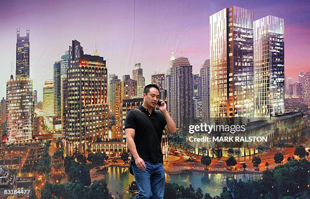 Chinese man walks past a billboard promoting a new property development under construction in Shanghai on October 9, 2008. China's presence on the...