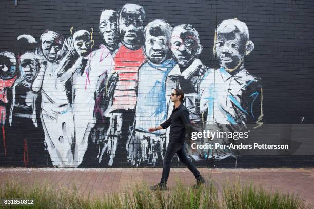 Property developer Jonathan Liebmann walks past a graffiti wall close to his office in Maboneng district on March 22, 2016 in downtown Johannesburg,...