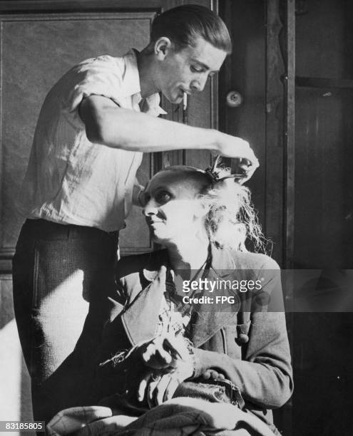 French woman accused of collaboration, or consorting with Germans, has her head shaved in retribution by a member of the Maquis, circa 1944.