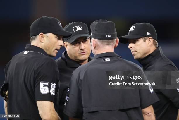 Home plate umpire Dan Iassogna and third base umpire Eric Cooper and second base umpire Lance Barksdale and first base umpire Tripp Gibson gather to...