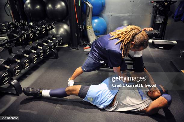 Assistant coach Steve Hess stretches Carmelo Anthony of the Denver Nuggets during practice on October 9, 2008 at the Pepsi Center in Denver,...