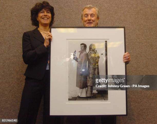 Photographer Terry O'Neill holds an iconic photograph taken by him of footballers Bobby Moore and Franz Beckenbauer with the widow of Moore,...