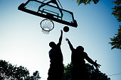 Two young men playing basketball on outdoor court