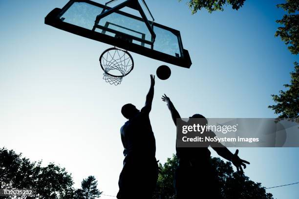 two young men playing basketball on outdoor court - linebacker stock pictures, royalty-free photos & images