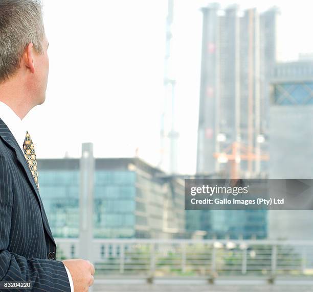 rear view of businessman looking out window, dubai cityscape in background, uae - difc stock-fotos und bilder