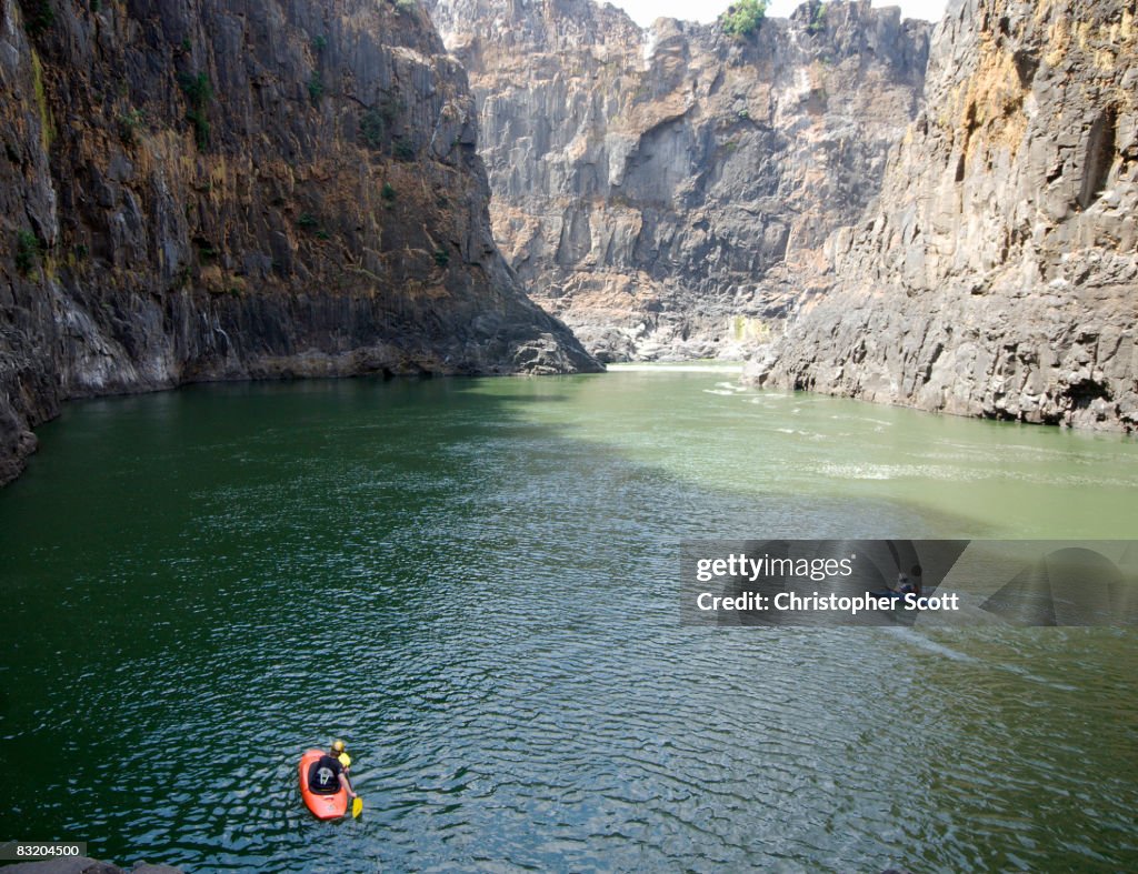 Two kayakers begin paddling upstream on the Zambezi river, Victoria Falls, Matabeleland North, Zimbabwe