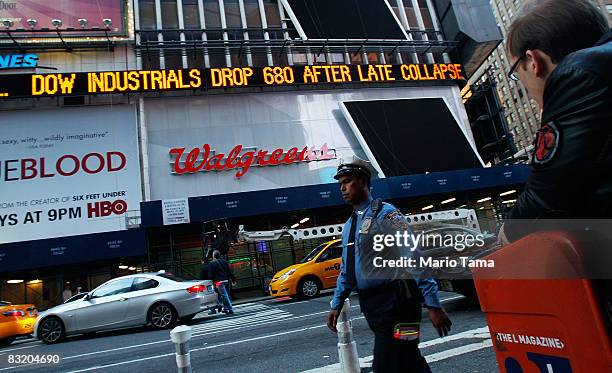 People are seen beneath a Times Square news ticker reading "Dow Industrials Drop 680 After Late Collapse" October 9, 2008 in New York City. The Dow...