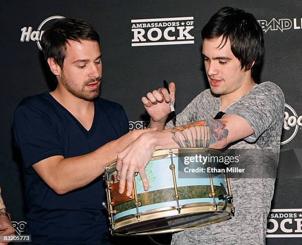 Panic at the Disco bassist Jon Walker and frontman Brendon Urie sign a drum as they donate it to the Hard Rock Cafe Las Vegas during a pre-concert...