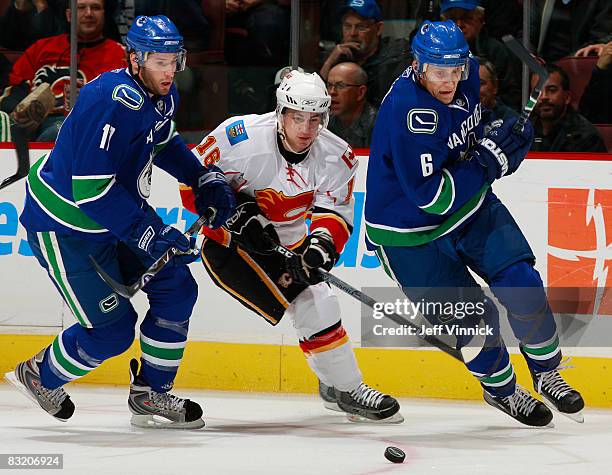 Dustin Boyd of the Calgary Flames and Ryan Kesler and Sami Salo of the Vancouver Canucks skate to the puck during their game at General Motors Place...