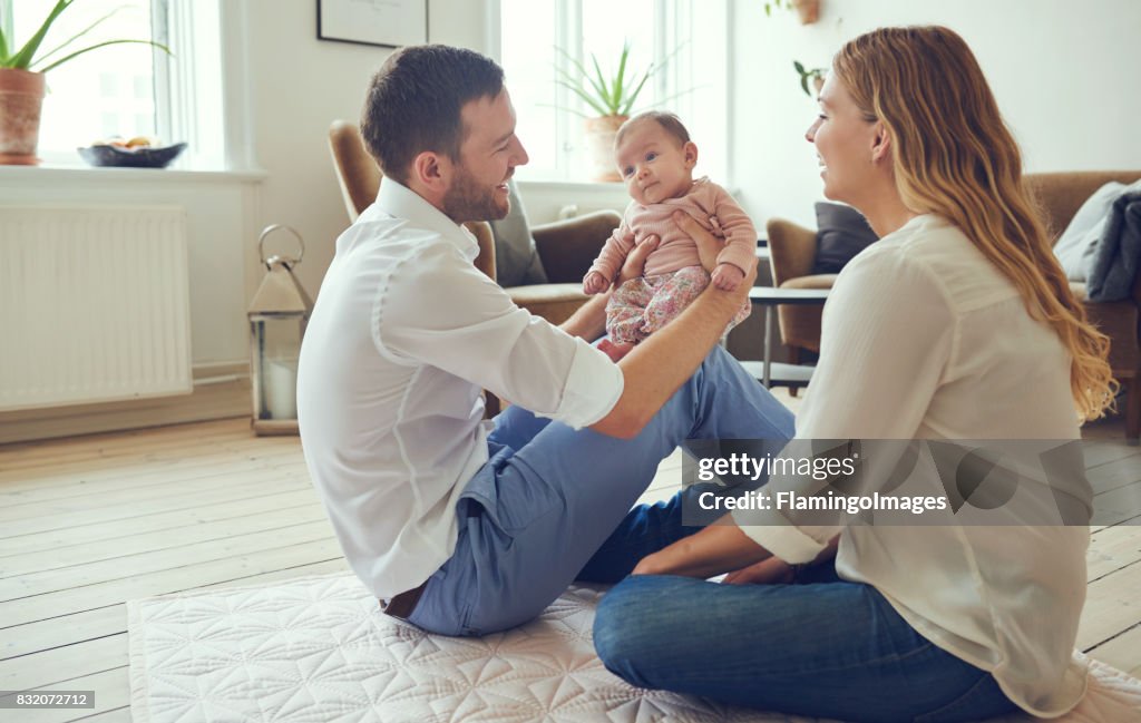 Smiling young parents sitting with their baby girl at home