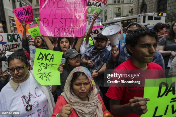 Demonstrators hold signs during the "Defend DACA & TPS" rally outside of Trump Tower in New York, U.S., on Tuesday, Aug. 15, 2017. A day after...