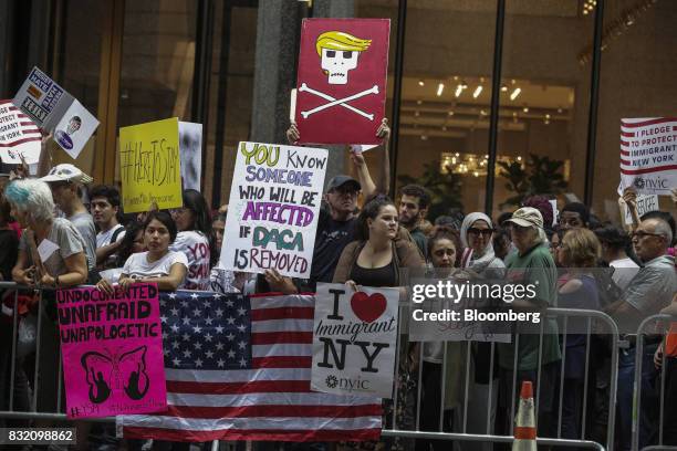 Demonstrators hold signs during the "Defend DACA & TPS" rally outside of Trump Tower in New York, U.S., on Tuesday, Aug. 15, 2017. A day after...