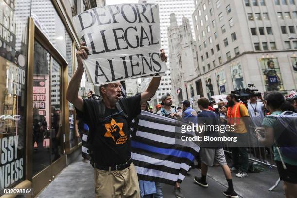 Counter-protester holds a sign while walking past demonstrators during the "Defend DACA & TPS" rally outside of Trump Tower in New York, U.S., on...