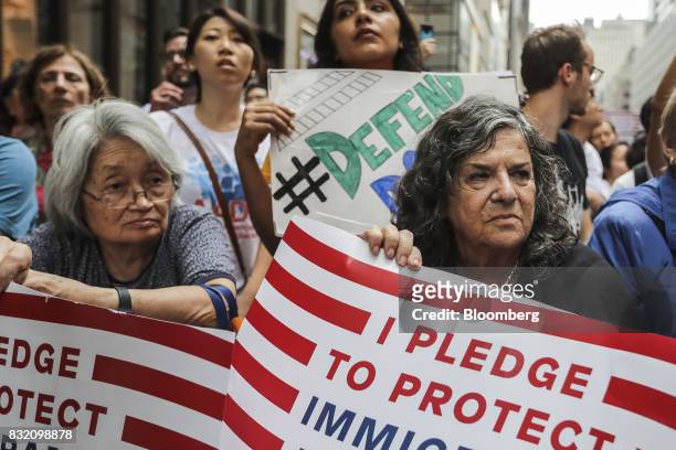 Demonstrators hold signs during the "Defend DACA & TPS" rally outside of Trump Tower in New York, U.S., on Tuesday, Aug. 15, 2017. A day after...