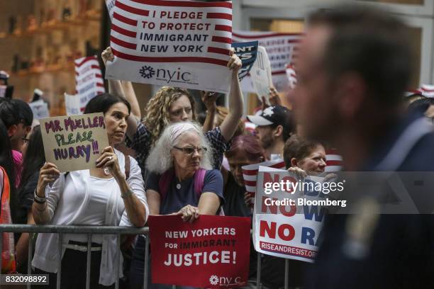 Demonstrators hold signs during the "Defend DACA & TPS" rally outside of Trump Tower in New York, U.S., on Tuesday, Aug. 15, 2017. A day after...