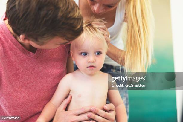 young child being swarmed by his loving parents. - babyhood stock pictures, royalty-free photos & images