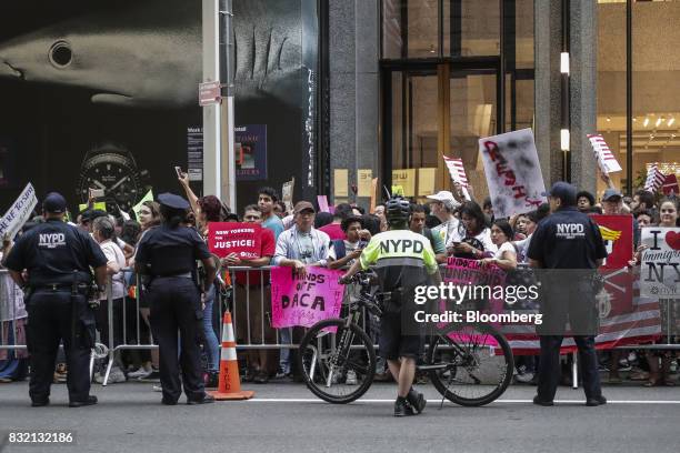 Demonstrators hold signs during the "Defend DACA & TPS" rally outside of Trump Tower in New York, U.S., on Tuesday, Aug. 15, 2017. A day after...