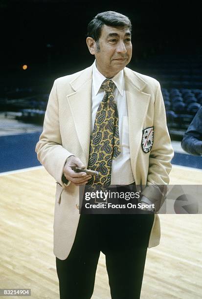 S - ABC sports media commentator Howard Cosell smoking a cigar on a basketball court.