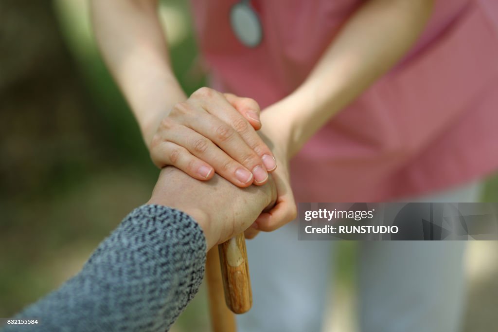 Image of a nurse holding the hand of an old man
