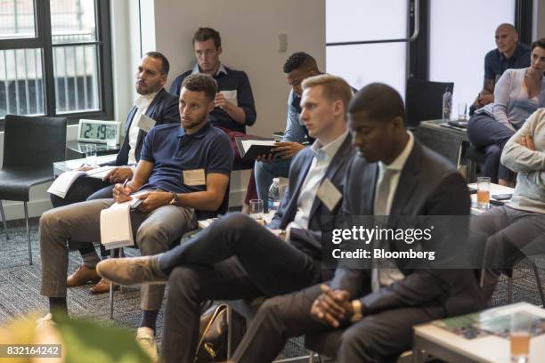 Stephen Curry, a professional basketball player with the National Basketball Association's Golden State Warriors, second left, listens to a panel...