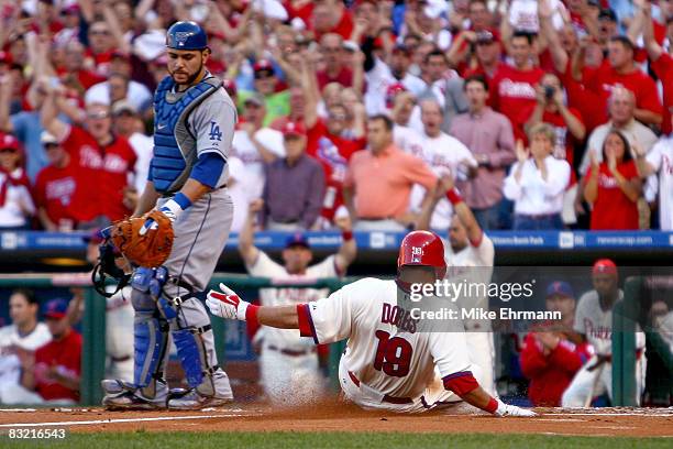 Greg Dobbs of the Philadelphia Phillies scores on a RBI double by Carlos Ruiz in the bottom of the second inning as catcher Russell Martin of the Los...