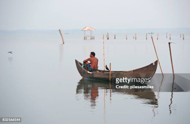 los pescadores de kerala espera pacientemente, kumarakom, lago vembanad, sur de la india. - dugout canoe fotografías e imágenes de stock