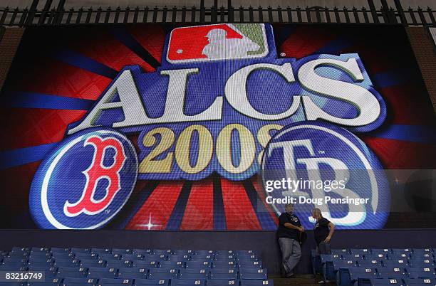 Fans stand below a screen displaying the ALCS matchup logo between the Boston Red Sox and the Tampa Bay Rays before game one of the American League...