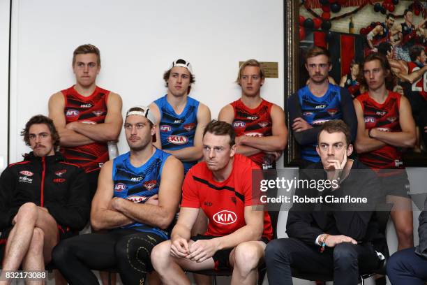 Bombers players look on as James Kelly of the Bombers speaks to the media during a press conference to announce his retirement at the Essendon...