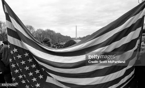 Washington, DC : An American Flag is held up in front of the camera, by Anti-Vietnam activists in Washington, DC. The Washington Monument, and...