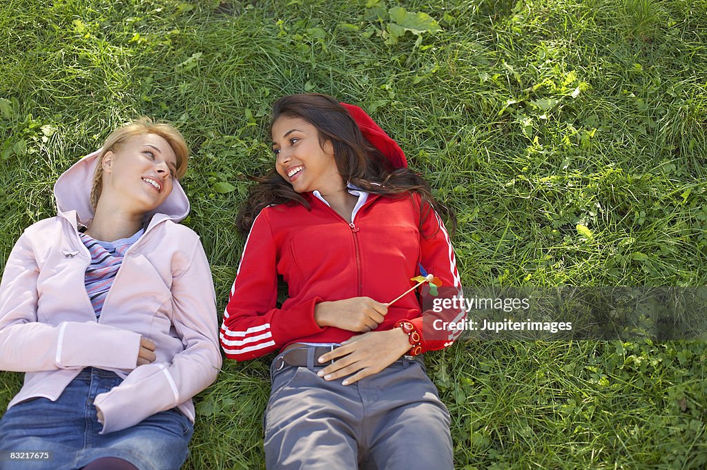 Smiling teenage girls lying on grass