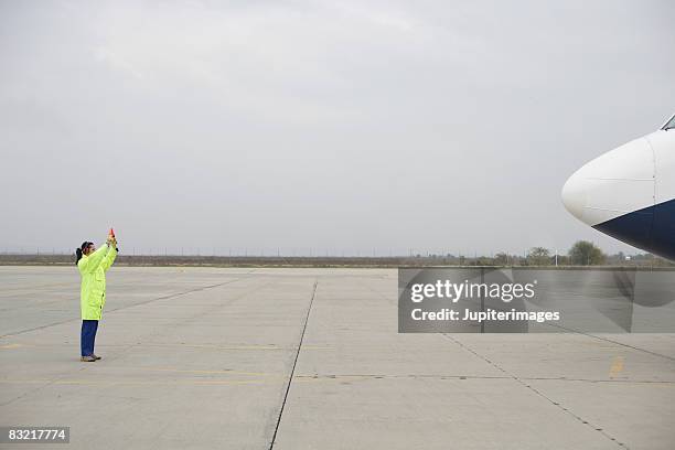 airport worker directing airplane - tarmac stockfoto's en -beelden