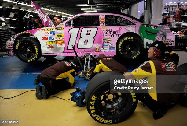 Crew members work on the M&M's/Susan G. Komen Toyota, driven by Kyle Busch, in the garage during practice for the NASCAR Sprint Cup Series Bank of...