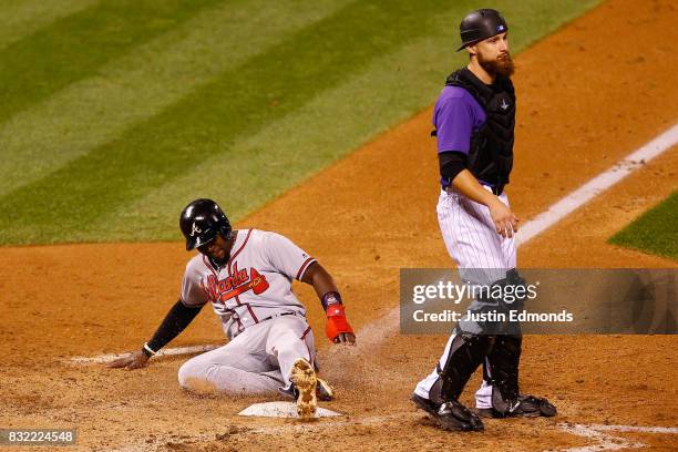 Brandon Phillips of the Atlanta Braves slides in for the go-ahead run in the eighth inning on a throwing error by Nolan Arenado of the Colorado...