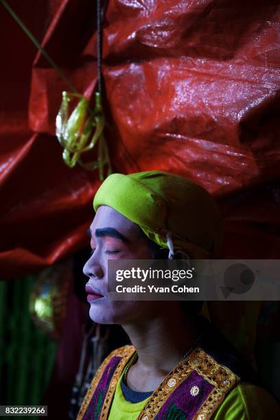 Chinese opera performer takes a moment to reflect as he waits behind the scenes during a performance in the Chinatown area of Bangkok.