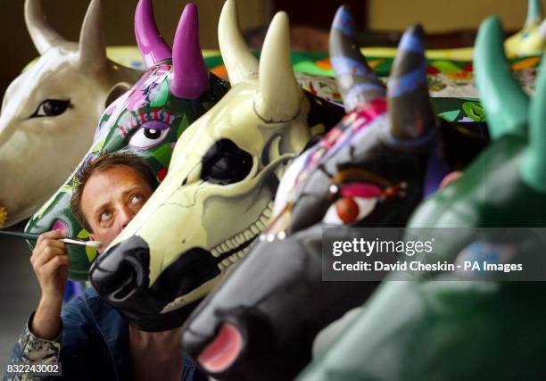 Nial Smith, an artist for Edinburgh's CowParade, adding the finishing touches to refurbish the collection of cows which will be auctioned on...