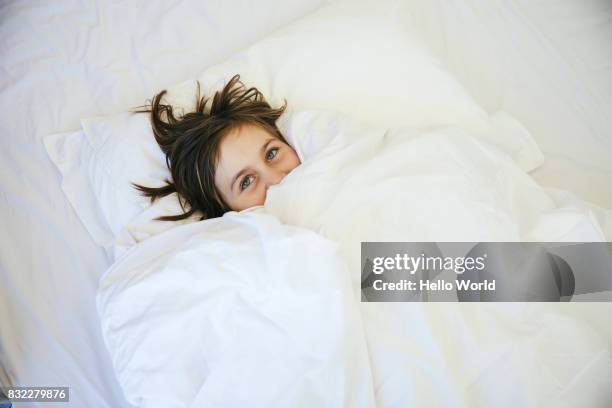 young girl lying under duvet - piumone foto e immagini stock