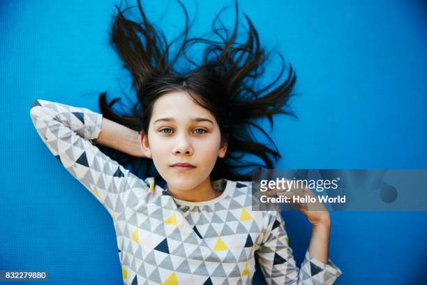 girl lying on blue background, looking at camera - child kid series expressions imagens e fotografias de stock