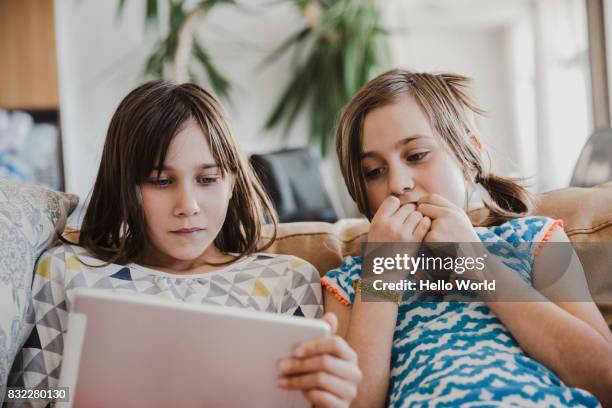 Two girls looking at tablet on couch