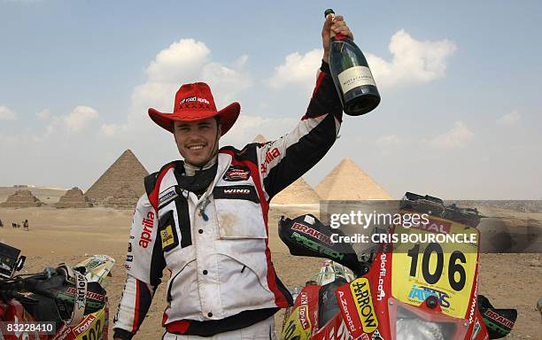 Third placed Italian motorcyle rally driver Paolo Ceci of the Aprilia Giolfi team psoes with a bottle of champagne in front of the Pyramids at the...