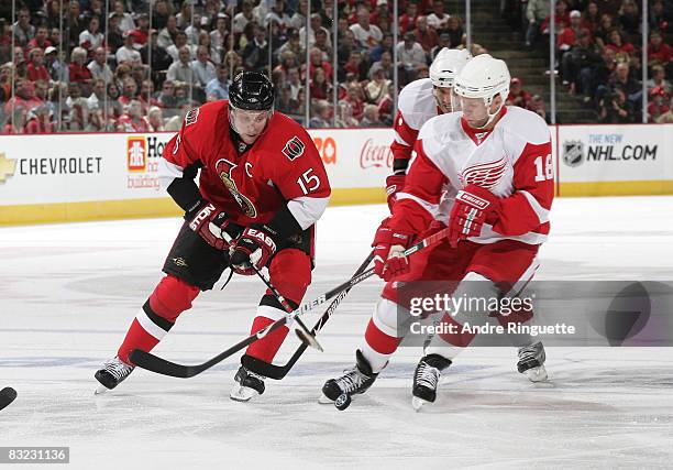 Dany Heatley of the Ottawa Senators stickhandles the puck into the offensive zone against pressure from Kirk Maltby of the Detroit Red Wings at...