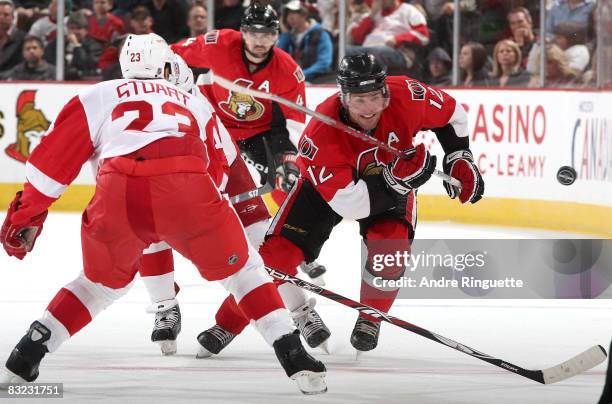 Mike Fisher of the Ottawa Senators chips the puck past Brad Stuart of the Detroit Red Wings at Scotiabank Place on October 11, 2008 in Ottawa,...