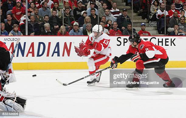 Pavel Datsyuk of the Detroit Red Wings fires a backhand shot as Chris Phillips of the Ottawa Senators reaches for a deflection at Scotiabank Place on...