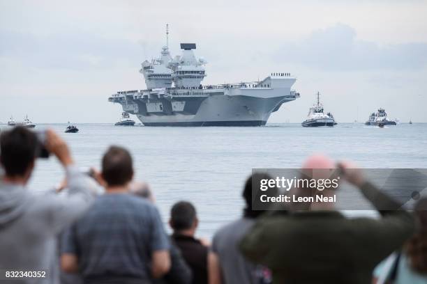 Members of the public gather to witness the arrival of the HMS Queen Elizabeth supercarrier as it heads into port on August 16, 2017 in Portsmouth,...