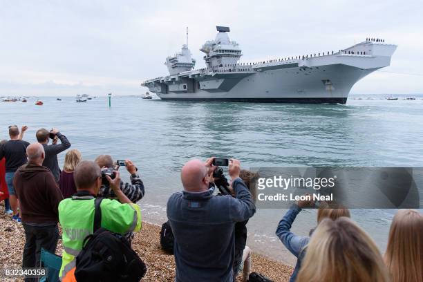 Members of the public gather to witness the arrival of the HMS Queen Elizabeth supercarrier as it heads into port on August 16, 2017 in Portsmouth,...