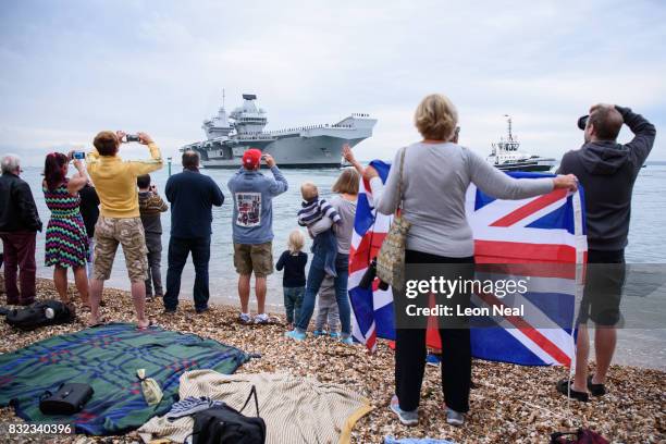 Members of the public gather to witness the arrival of the HMS Queen Elizabeth supercarrier as it heads into port on August 16, 2017 in Portsmouth,...