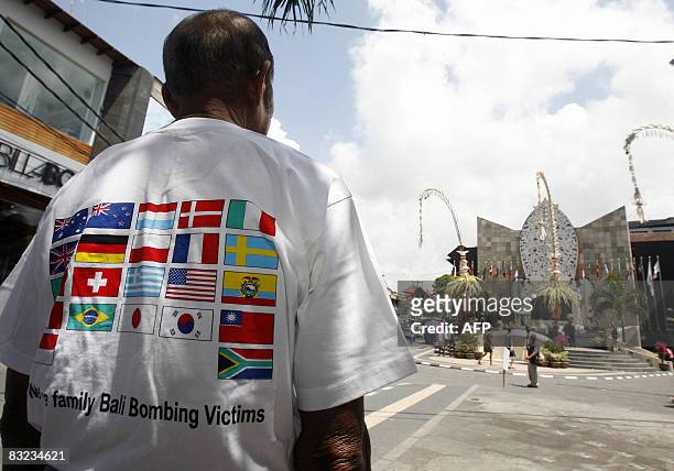 Man, wearing a T-shirt representing the 22 different countries from where the 202 victims of the 2002 Bali bombing came from, looks across the street...