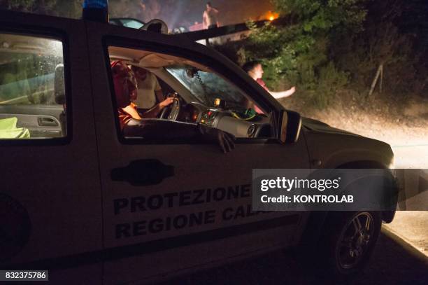 Volunteers work to extinguish a vast fire in Sila, with fire truck , in Calabria, southern Italy.