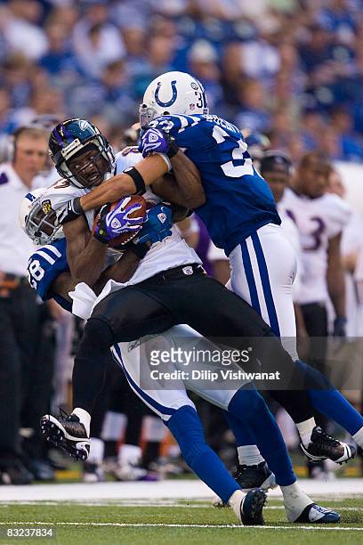 Derrick Mason of the Baltimore Ravens is tackled by Marlin Jackson and Melvin Bullitt both of the Indianapolis Colts at Lucas Oil Stadium on October...